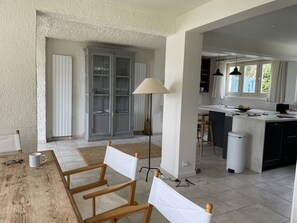 Eine moderne Küche mit einer zentralen Kochinsel, einem Essbereich mit Holzkästen und einem großen Schrank mit Glastüren.