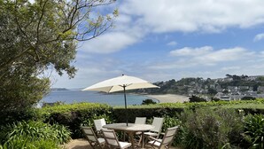 Une terrasse avec une table et des chaises, donnant sur une plage et une ville.