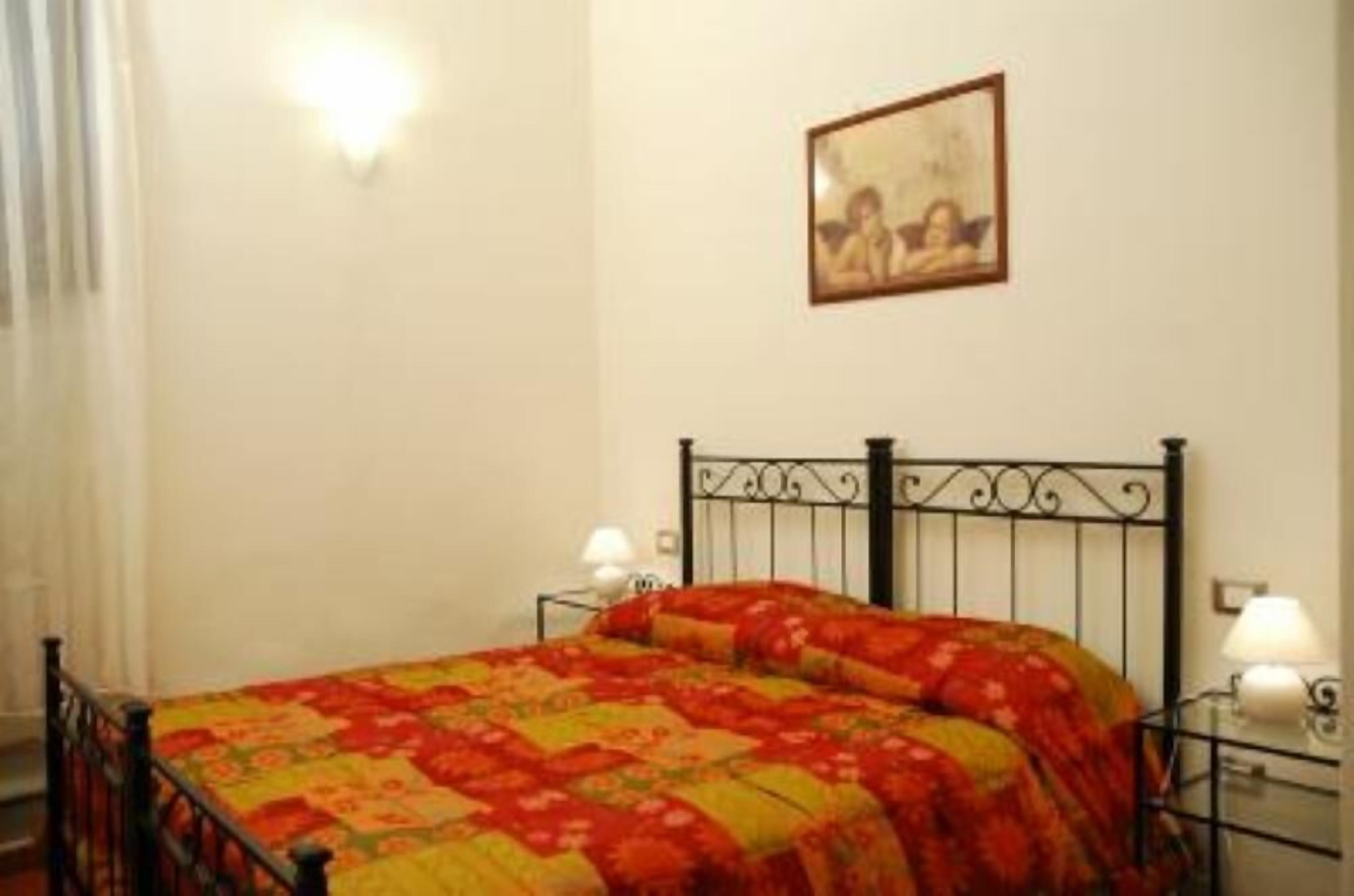 Un dormitorio con cama, dos lámparas de noche, un cuadro en la pared y una ventana con cortinas.