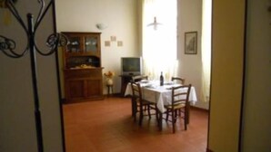 A dining area with a table set for four, a television, and a cabinet with glass doors. - apartment in Santa Croce 52 in Florence ( Italy) (Firenze)