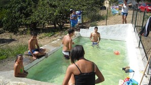 Une zone autour d’une piscine où des personnes sont assises et se tiennent debout.