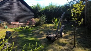 A rustic outdoor area with a wooden bench, a stone structure, and a tree.