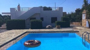 A rectangular swimming pool with a clear blue water surface, surrounded by stone tiles.