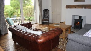 A living room with a brown leather sofa, a grey sofa, a wooden coffee table, and a fireplace. - Gorgeous Lakeland cottage with delightful private garden. Free EV charging. (Stainton)