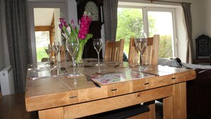A wooden dining table set with wine glasses, cutlery, and a vase of flowers. - Gorgeous Lakeland cottage with delightful private garden. Free EV charging. (Stainton)