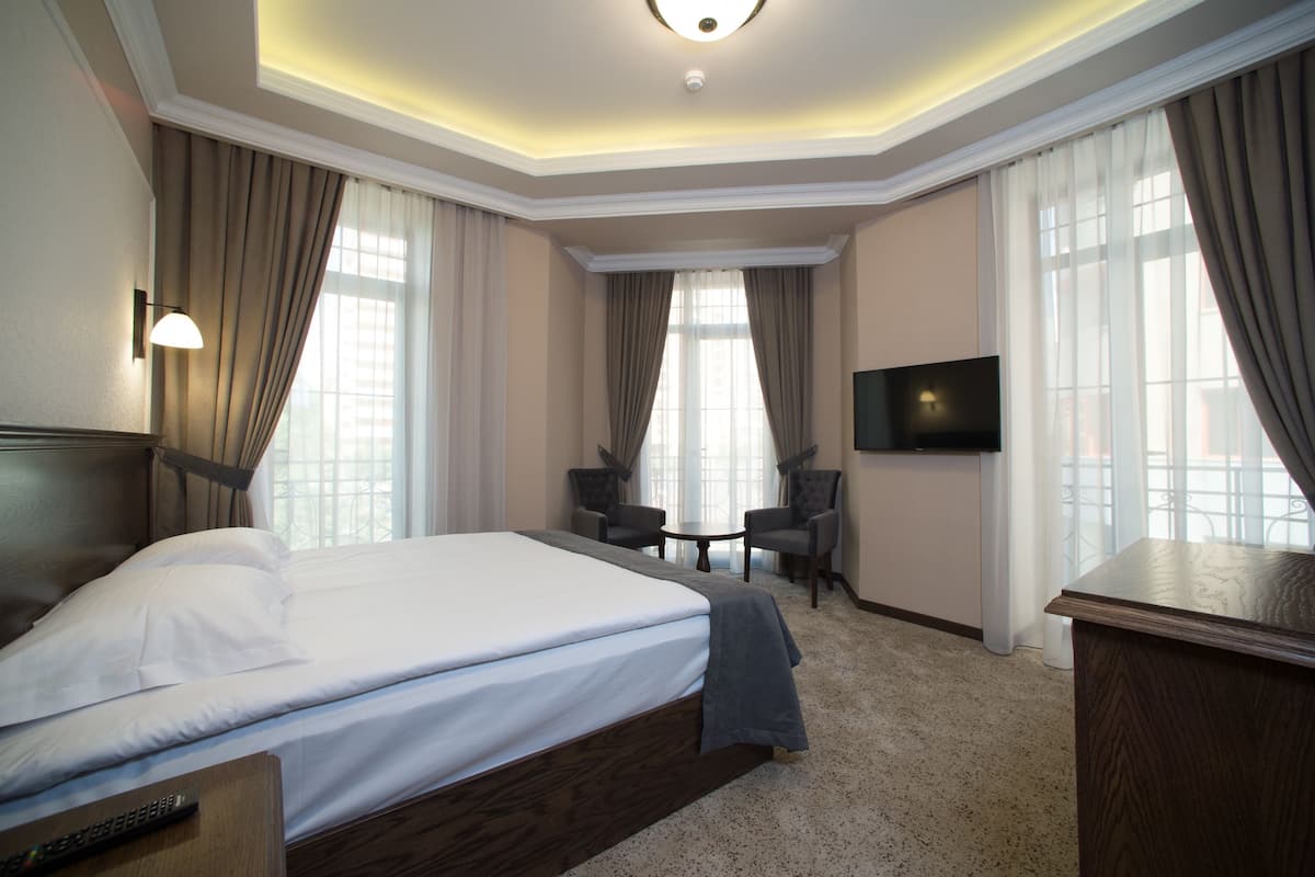 Une chambre d’hôtel avec un grand lit, une télévision, un bureau et deux chaises.