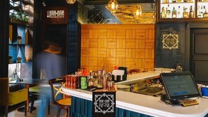 A bar area with a wooden counter, bar stools, and a menu display. - Boulevard Hotel (Yerevan)