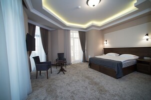 Een hotelkamer met een groot bed, een bureau, een stoel en een televisie.