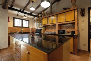 A kitchen with wooden cabinets, a large island, and a microwave.