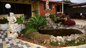 Un patio con una fuente, plantas en macetas y una estatua.