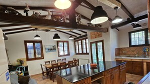 A spacious kitchen with a large island, wooden cabinets, and a dining area with chairs.