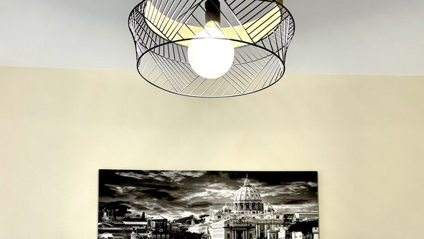 A bedroom with a bed, a wall-mounted picture of a bridge, a hanging light fixture, and a striped headboard. - BLASERNA HOUSE "in the heart of shopping in Rome" (Roma)