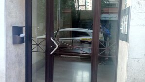 A glass door entrance with a metal gate, a concrete floor, and a visible car parked outside. - BLASERNA HOUSE "in the heart of shopping in Rome" (Roma)