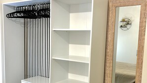 A white wardrobe with multiple shelves and a hanging rack, a mirror with a wooden frame, and a wooden floor. - BLASERNA HOUSE "in the heart of shopping in Rome" (Roma)