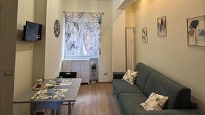 A living room with a sofa, a coffee table, and a TV mounted on the wall. - BLASERNA HOUSE "in the heart of shopping in Rome" (Roma)
