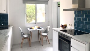 Une cuisine moderne avec des meubles blancs, une cuisinière noire et une fenêtre donnant sur un paysage verdoyant.