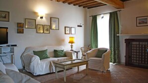 Un accogliente soggiorno con divano, poltrone, tavolino e televisore.