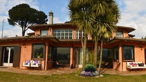 A two-story house with a patio area, large windows, and a palm tree. - Magic luxury villa, swimming pool, SPA, tennis, wooded park. (Valmontone)