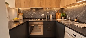 A modern kitchen with a built-in oven, a coffee maker, and a sink.