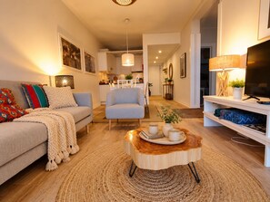 Ein stilvolles Wohnzimmer mit einer Couch, Sesseln, einem Couchtisch und einem Fernseher.