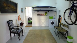 A compact living space with a chair, a small table, a washing machine, and a bicycle mounted on the wall.