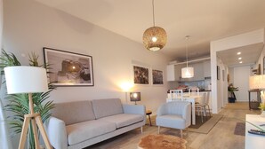 Una sala de estar moderna con sofá, sillones, una mesa de centro y un comedor con mesa y sillas.