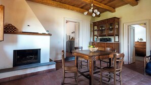 Een rustiek interieur met een open haard, een houten eettafel en een keuken met kastjes.