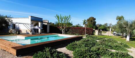Et moderne hus med swimmingpool, havemøbler og en velholdt have.
