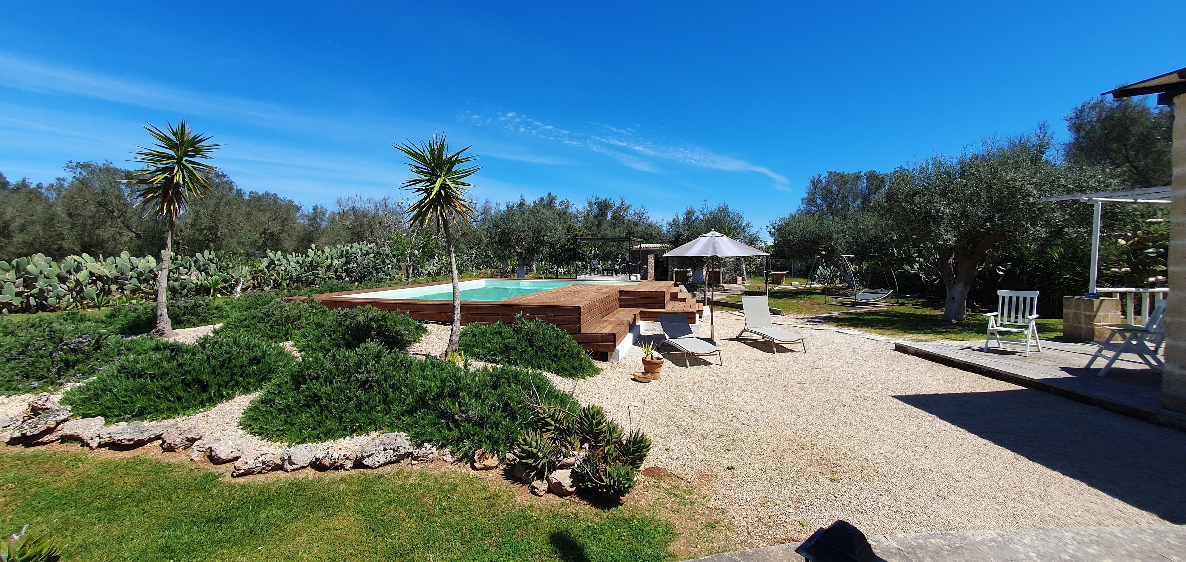 A pool area with a wooden deck, lounge chairs, and a gazebo.