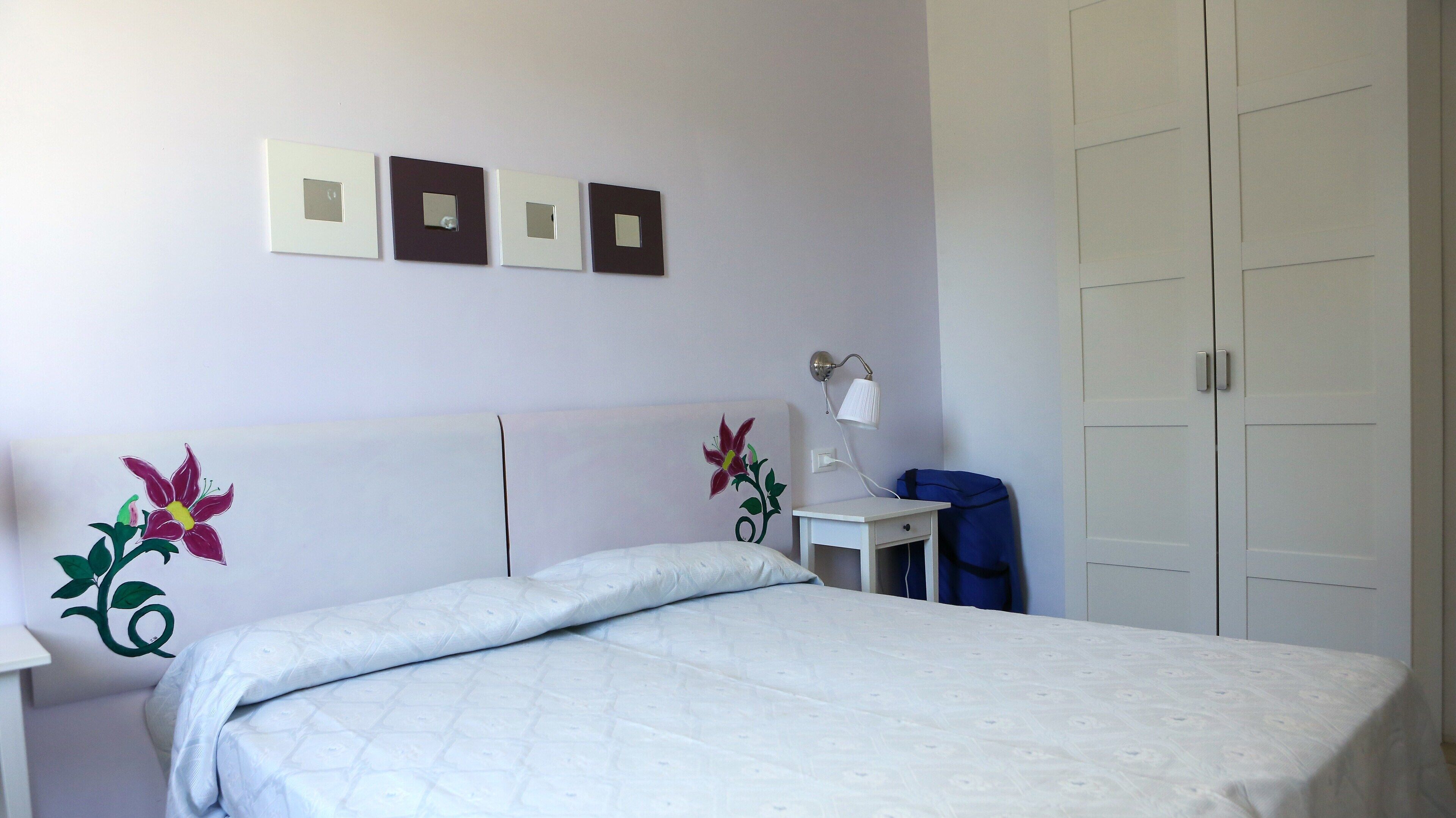 A bedroom with a bed, a nightstand, a lamp, and a wardrobe.