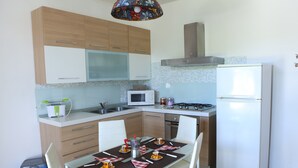 A compact kitchen with wooden cabinets, a microwave, a gas stove, and a refrigerator. - HOUSE WITH GARDEN AND SWIMMING POOL FOR EXCLUSIVE USE IN SALENTO, OTRANTO, LECCE (corigliano d' otranto)