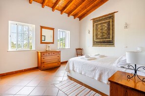 Un dormitorio con cama, cómoda de madera, silla, mesita de noche y un adorno en la pared.