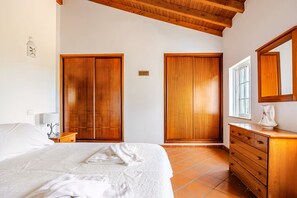 A bedroom with a bed, wooden wardrobe, a dresser, and a window.