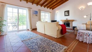 Ein geräumiges Wohnzimmer mit hohen Holzbalkendecken, einem Kamin, einem Sofa und einem Couchtisch.