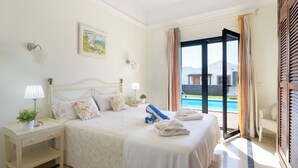 A hotel room with a bed, bedside tables, a lamp, a painting, and a view of a swimming pool. - Luxury villa, heat pool ,ecological, chlorine-free  ,Jacutzzi / bicycl (Yaiza)