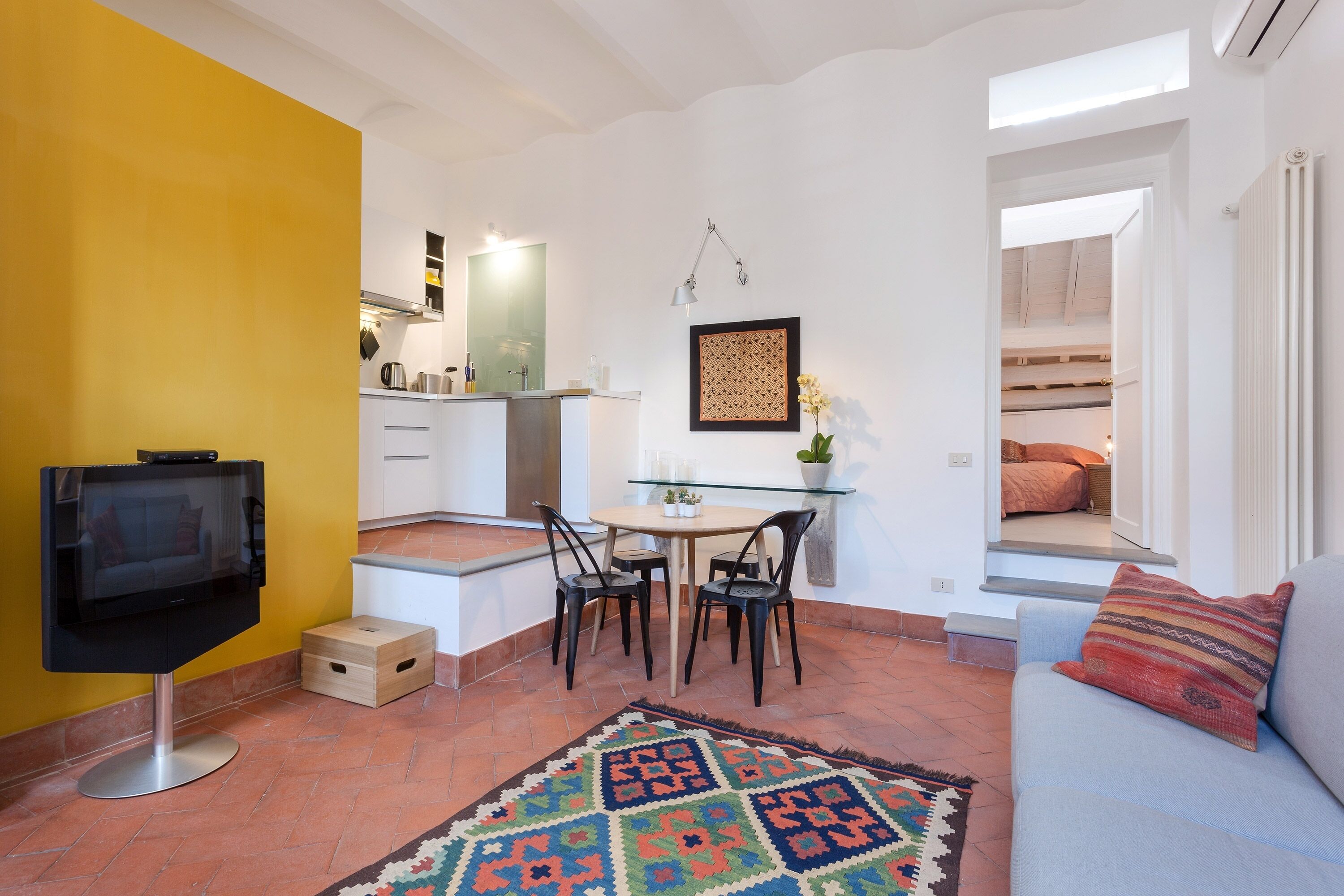 A compact living space with a TV, dining area, and a sofa.