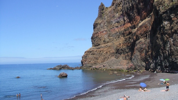 A beach with rocky cliffs, calm sea, and people sunbathing. - Marina Sol Penthouse <br>- Sea view - Free Wifi (Madalena do Mar)