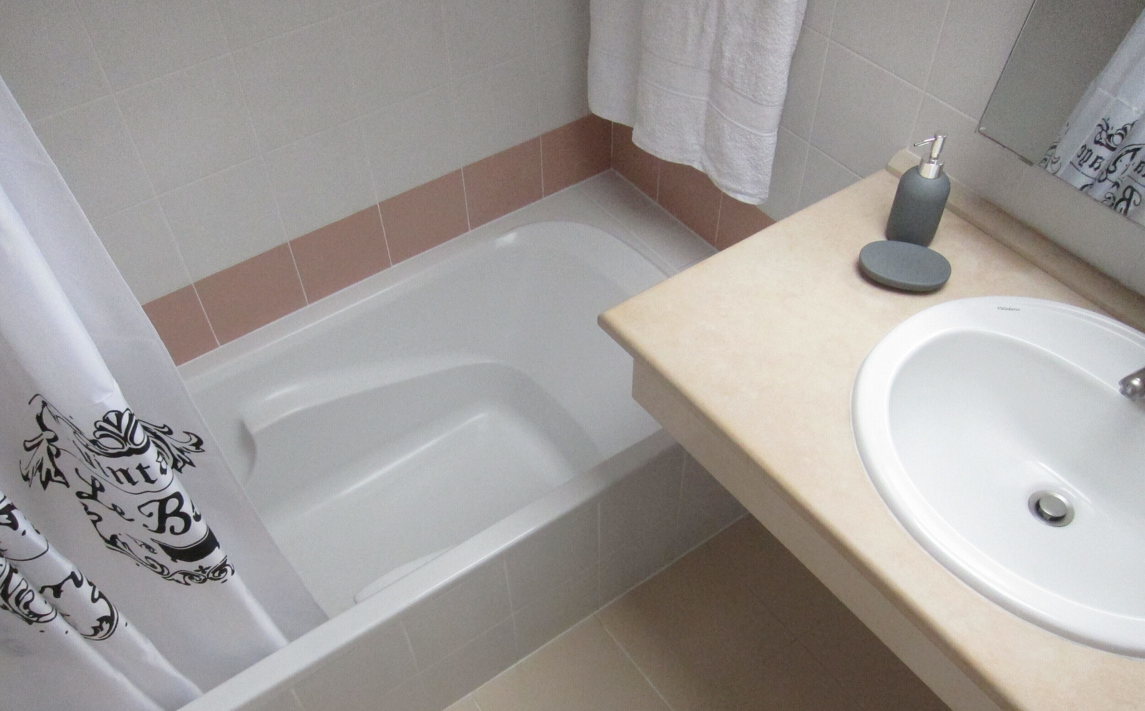 Une salle de bain avec une baignoire, un lavabo et un porte-serviettes.