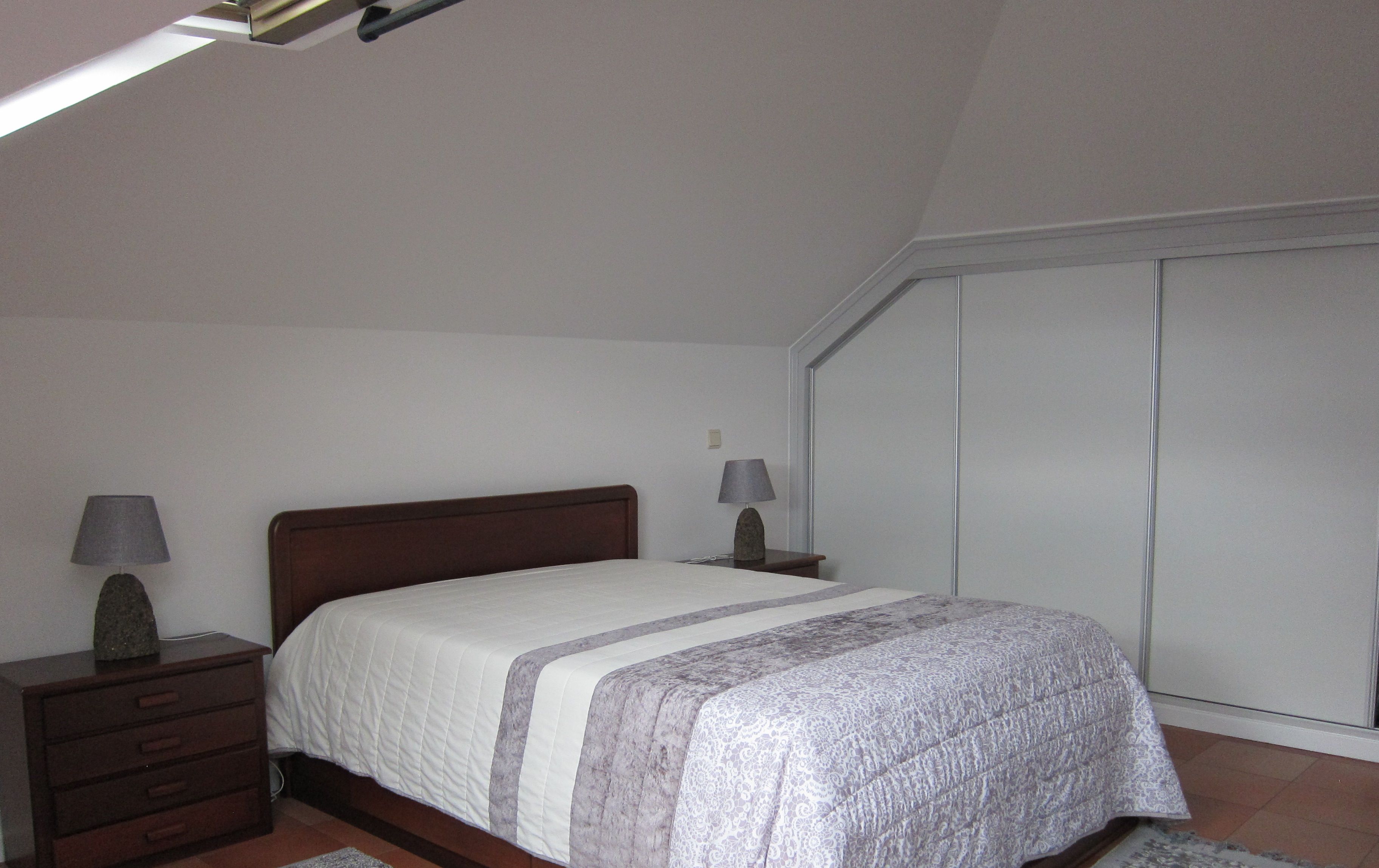 Une chambre à coucher avec un lit, des tables de chevet et une armoire.