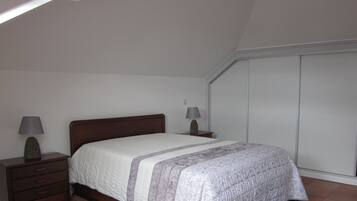 Une chambre à coucher avec un lit, des tables de chevet et une armoire.