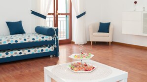 Ein Zimmer mit Bett, Stuhl, Tisch und einem Vorhangfenster.