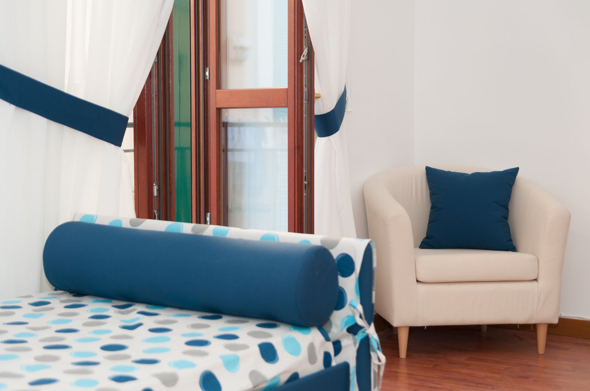 Une chambre à coucher avec un lit, une chaise et une fenêtre avec des rideaux.