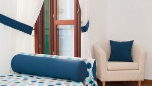 Ein Schlafzimmer mit Bett, Stuhl und einem Vorhangfenster.
