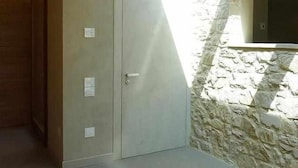 Una habitación con pared de piedra, techo de madera y una puerta con pomo.