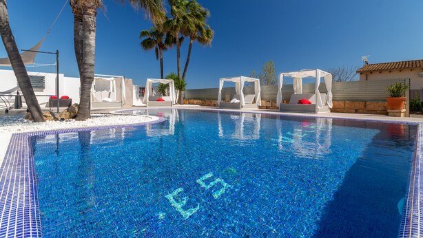 A clear blue pool with white sun loungers and palm trees. - Es Garrover Es Velar with XXL pool, playground, volleyball, billiards, gym.. (Muro)