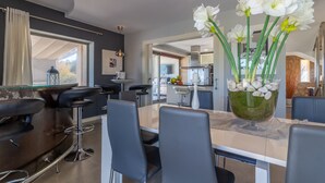 A modern dining area with a glass-top table, black chairs, and a vase of white flowers. - Es Garrover Es Velar with XXL pool, playground, volleyball, billiards, gym.. (Muro)