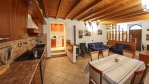 Une cuisine avec des meubles de rangement en bois, une cuisinière et un coin repas comprenant une table et des chaises.