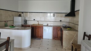Una cocina compacta con lavavajillas integrado, estufa a gas y pileta.