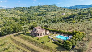 Una villa de piedra con piscina, rodeada de abundante vegetación y viñedos.