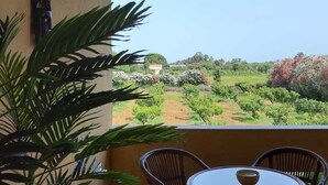 Un balcon agrémenté d’une table et de chaises, donnant sur un jardin aménag é avec des arbres et des arbustes.